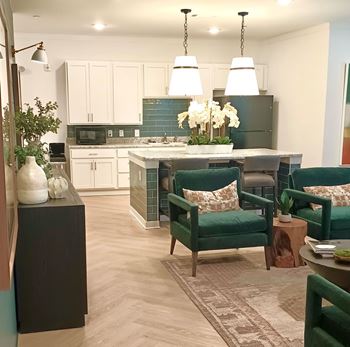 A kitchen with green chairs and a table with a vase of flowers on it.